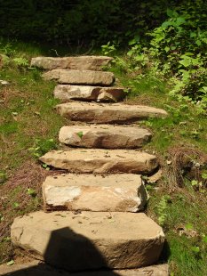 Rock steps to a wooded area behind the house by Gonzalez Landscaping and Home Improvement